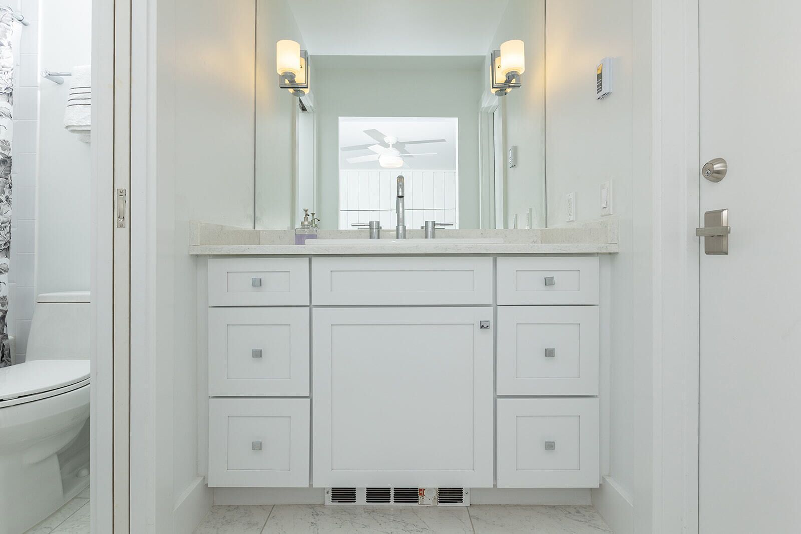 A bathroom with a white vanity, a mirror, and two wall-mounted lights.