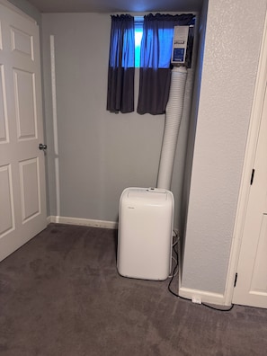 A room with a white door, a window with blue curtains, and a white portable heater. - 1 BRM Basement Apartment/ 420 friendly outside (Lakewood)