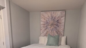 A bedroom with a bed, a headboard, a wall art piece, and a carpeted floor. - 1 BRM Basement Apartment/ 420 friendly outside (Lakewood)
