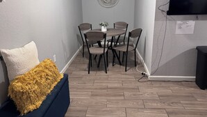 A room with a dining table and chairs, a TV mounted on the wall, and a small plant on the table. - 1 BRM Basement Apartment/ 420 friendly outside (Lakewood)