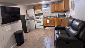 A compact kitchen with a refrigerator, microwave, stove, and oven. A black leather sofa is positioned in the living area. - 1 BRM Basement Apartment/ 420 friendly outside (Lakewood)