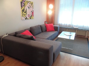 Una sala moderna con un sofá modular, una mesa de centro y un cuadro en la pared.