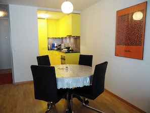 Un comedor con una mesa redonda, cuatro sillas y una cocina al fondo.