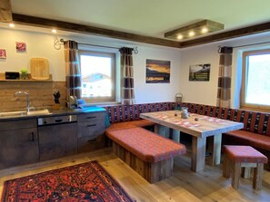Uma cozinha acolhedora com bancos de madeira, uma mesa de jantar e um tapete.