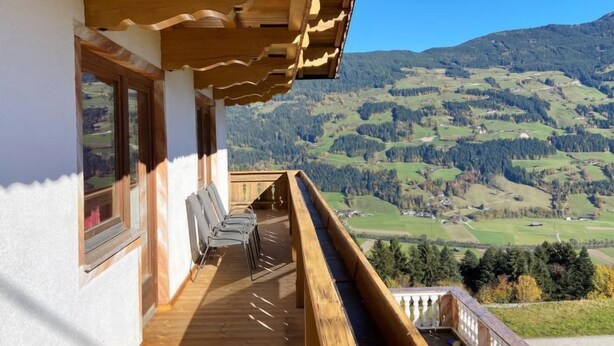 Ein hölzerner Balkon mit Blick auf eine gebirgige Landschaft.