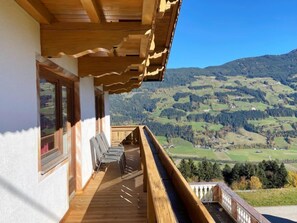 Un balcón de madera con vistas a un paisaje montañoso.