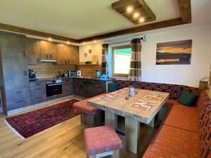 Cozinha moderna com armários de madeira, uma mesa de jantar e um sofá.