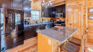 Una cucina moderna con mobili in legno scuro, elettrodomestici in acciaio inossidabile, piani in granito e un'isola in legno con posti a sedere.