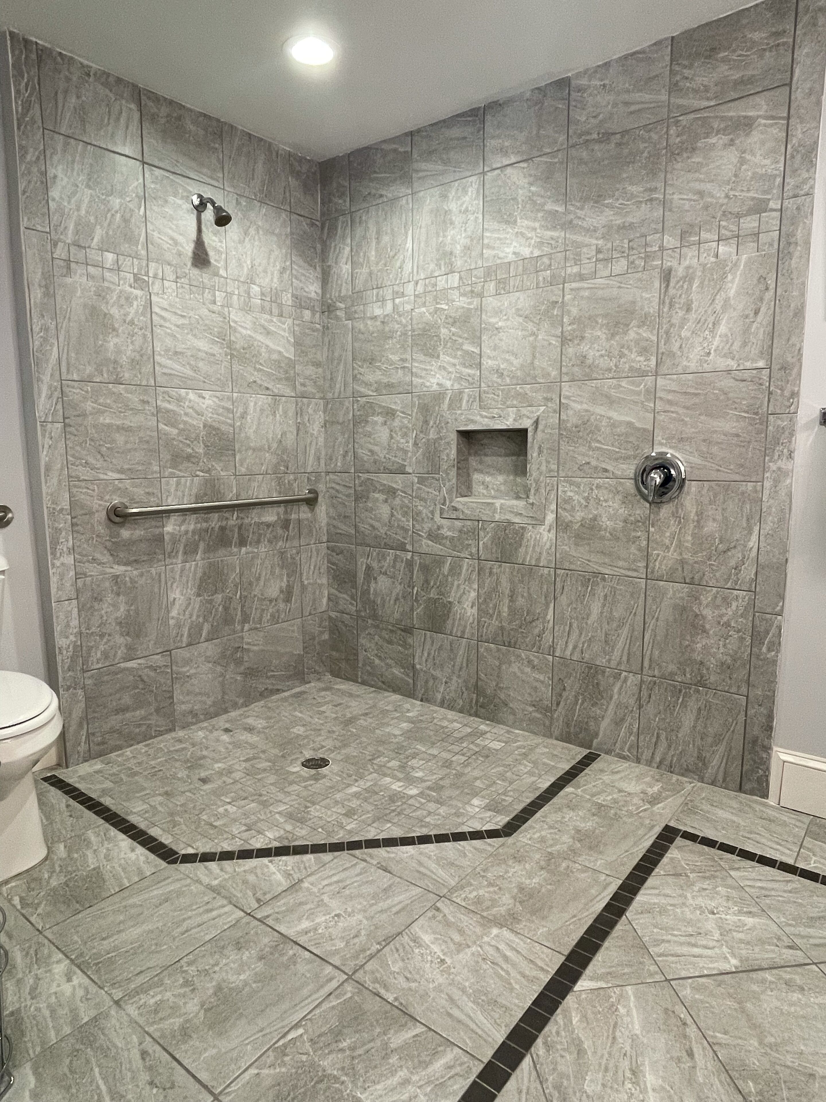 Une salle de bain avec une douche à l’italienne, des murs carrelés et des toilettes.