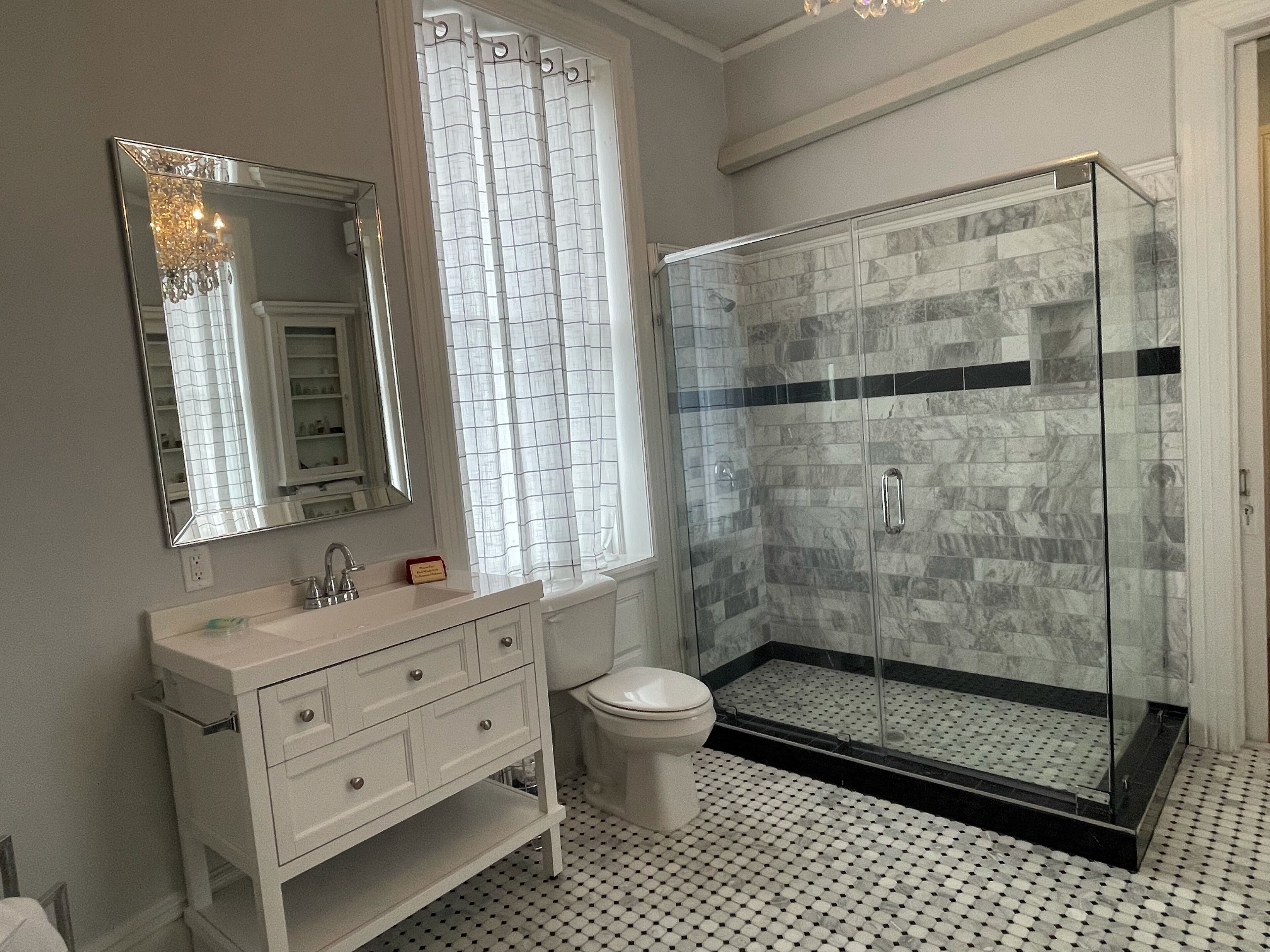 A bathroom with a glass-enclosed shower, a white sink, and a toilet.