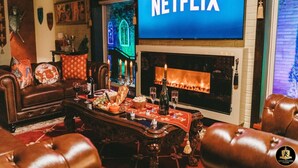 A cozy living room with a fireplace, a leather sofa, and a Netflix sign. - 🛡Medieval Castle Hôtel ™ (McAllen)