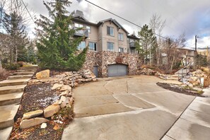 A residential property with a stone facade, a garage, and a driveway leading to a house with a balcony.