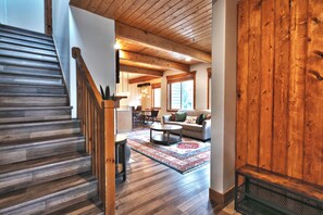A spacious living area with a wooden staircase, a sofa set, and a patterned rug.