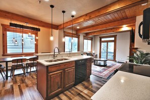 A kitchen with wooden cabinets, a central island, a dining area with chairs, and pendant lighting.