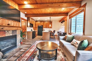 A spacious living area with a fireplace, a round coffee table, and a sofa with cushions.