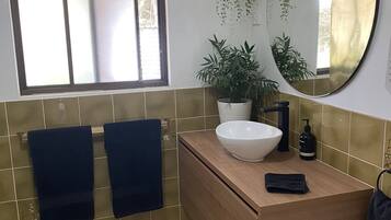 Een badkamer met een wit wastafel, een spiegel, en twee handdoeken aan de muur.