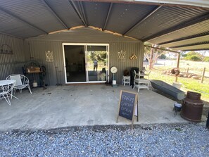 A covered outdoor seating area with a chalkboard sign indicating a farm shop is open. - Farm stay with alpacas at your doorstep (Cromer)