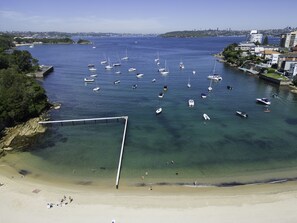 Un port de plaisance sur la côte, avec des bateaux amarrés, une plage de sable et, en arrière-plan, le profil de la ville.