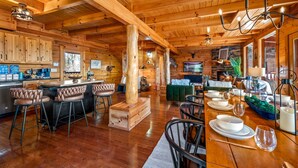 A spacious wooden cabin interior with a kitchen, dining area, and bar seating. - Log Cabin with Stunning Views- Hot Tub, Sauna, BBQ, Patio Fireplace, Pets ok (Sevierville)
