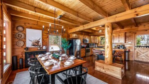 A rustic wooden cabin interior with a dining area, kitchen, and bar. - Log Cabin with Stunning Views- Hot Tub, Sauna, BBQ, Patio Fireplace, Pets ok (Sevierville)