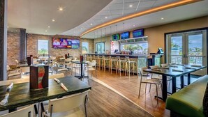 A modern restaurant with a bar area, multiple seating options, and large windows offering views.