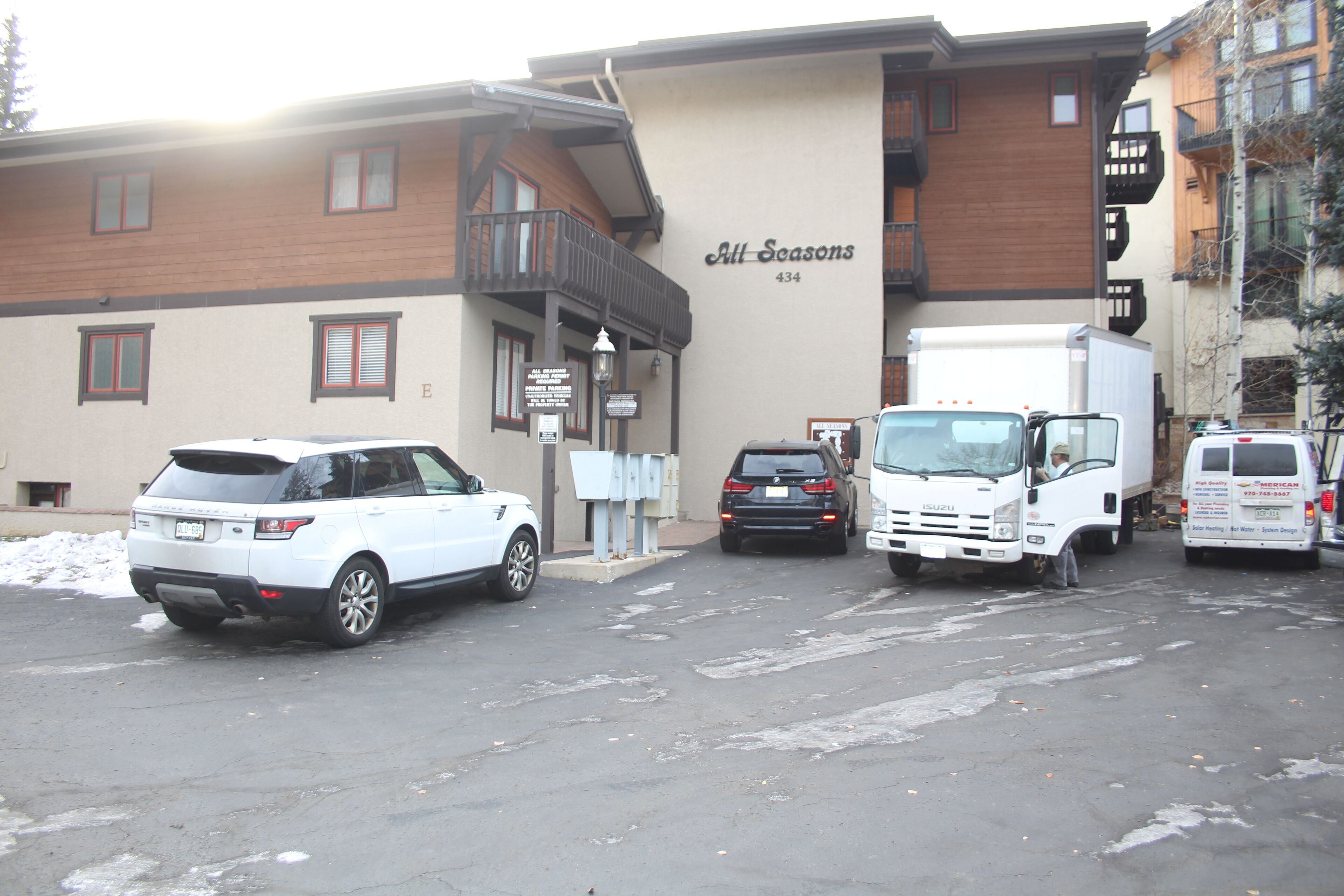 A parking lot with several vehicles, including a white SUV and a white truck.