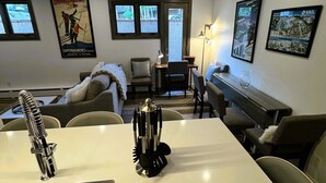 Una cocina moderna con un lavamanos de acero inoxidable, una zona de comedor con una mesa blanca y dos carteles enmarcados en la pared.