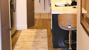 Una cocina moderna con refrigerador empotrado, armarios de madera, un taburete de bar y un perchero para esquíes.
