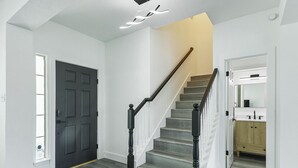 A staircase with wooden steps and black balusters, leading to a landing with a white door. - Newly Renovated Luxury 5BR – Family & Game Room (The Colony)