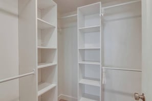 A white closet with multiple shelves and hanging space.