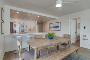 A modern kitchen with a central island, bar stools, and a dining table with chairs.