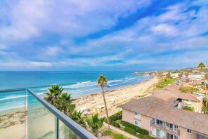 A coastal view from a balcony overlooking a beach with a clear sky.
