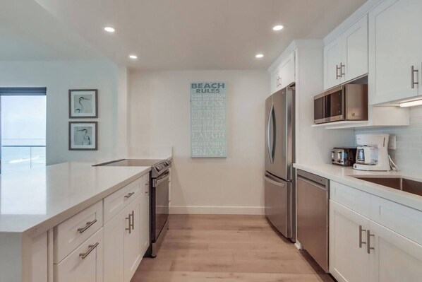 A modern kitchen with white cabinetry, stainless steel appliances, and a central island.