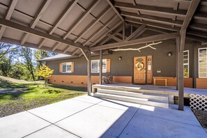 A covered porch with steps leading to a wooden door, a bench, and a wreath decoration. - Cheerful Home with Spa near Yosemite & Bass Lake (Oakhurst)