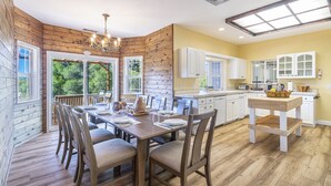 Een moderne keuken met houten wanden, witte kasten en een eethoek met een houten tafel en stoelen.