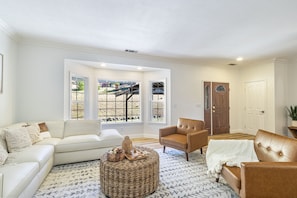 Relax in this stylish living room with a sofa, armchair, and ottoman, offering a view of the backyard.