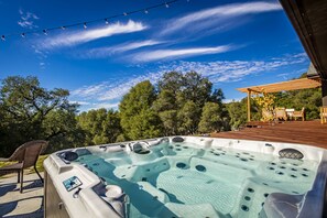 Relax in the hot tub surrounded by lush greenery and enjoy the serene atmosphere.