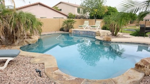 A swimming pool with lounge chairs, a hot tub, and a landscaped garden.