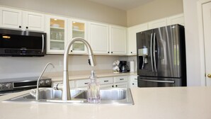 Una cucina moderna con elettrodomestici in acciaio inossidabile, un lavello a due vasche e mobili bianchi.
