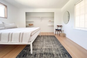 A bedroom with a bed, a chair, a small table, a mirror, and a closet with shelves. - Ocean View, Perfect for Agate Hunting! Dog Friendly! Fireplace! (Florence)