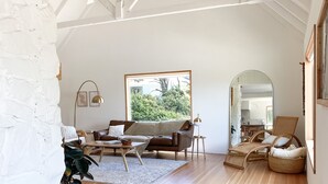 Un salón amplio con un gran ventanal, un sofá, una mesa de centro y un sillón.
