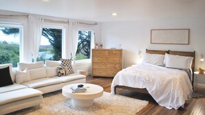 Une chambre moderne avec un grand lit, un canapé, une commode et une vue sur l’extérieur.