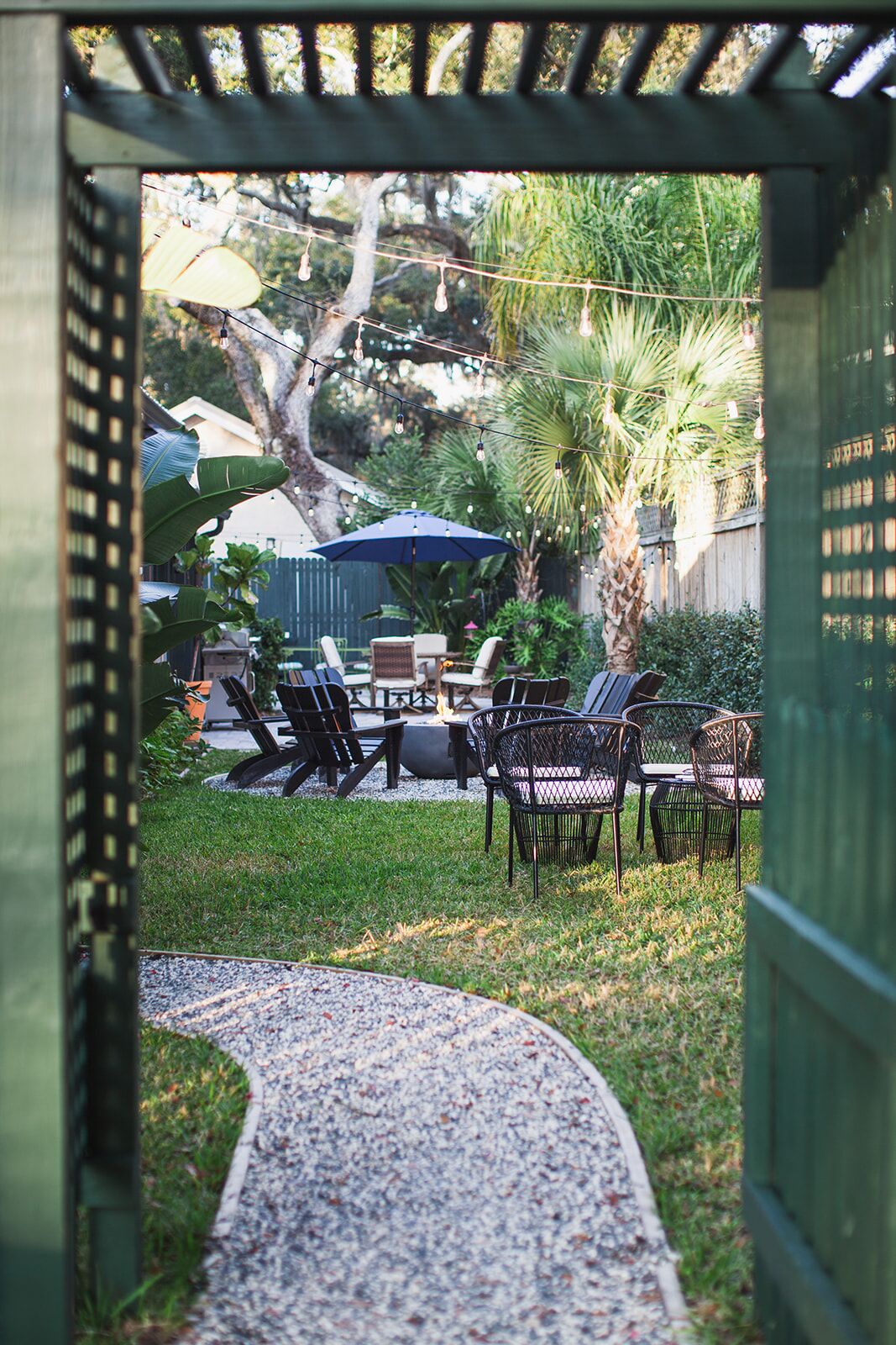 An outdoor patio area with a fire pit, seating, and string lights.