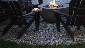 Eine Terrasse mit Feuerstelle, Sitzgelegenheiten und Lichterketten.