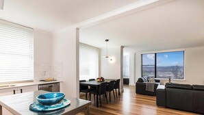Ein modernes Wohnzimmer mit Essbereich, großen Fenstern und Blick auf die Stadt.