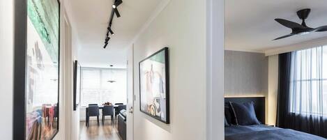 Habitación de hotel con cama, ventilador de techo, ventana con cortinas e imagen enmarcada en la pared.