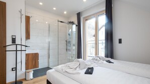 Un dormitorio moderno con una cama grande, zona de ducha y vistas al exterior.