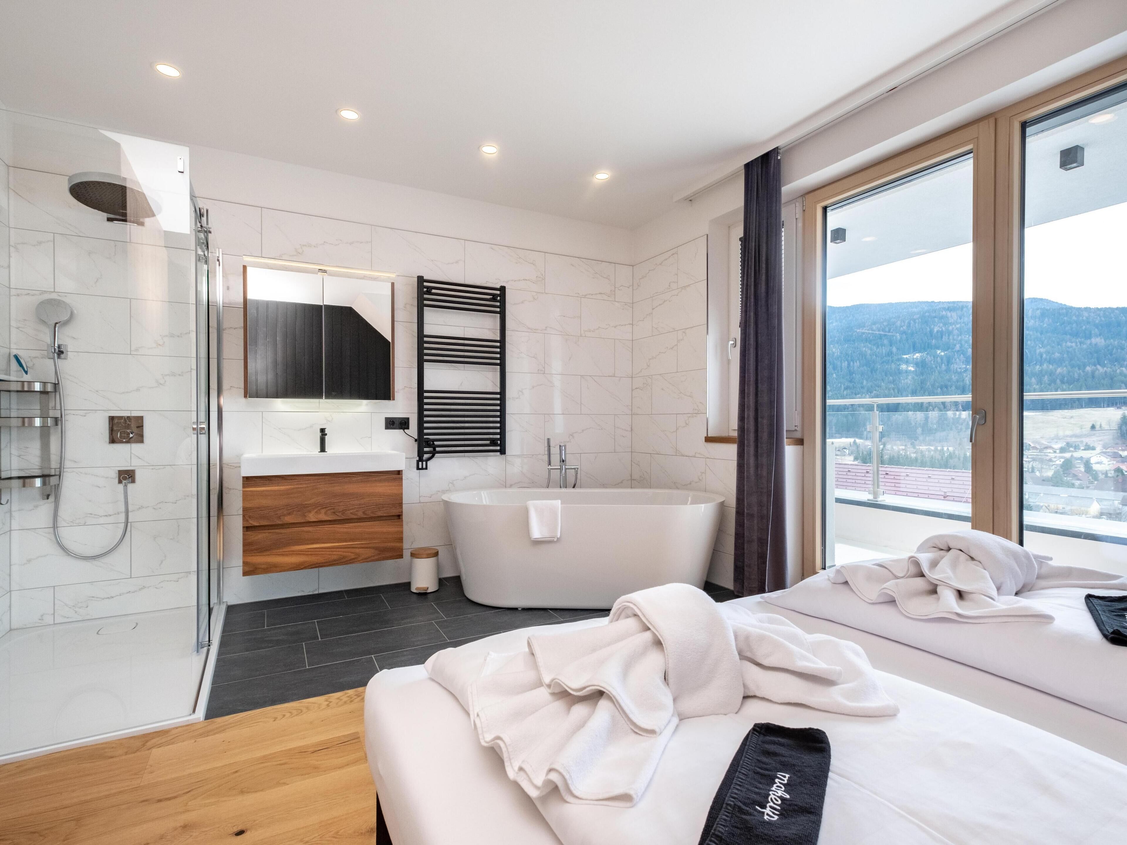 Un baño moderno con cabina de ducha de vidrio, una bañera independiente y un espejo grande.