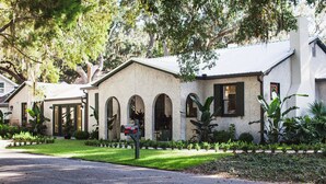 A house with a stucco exterior, arched windows, and a front yard with various plants.