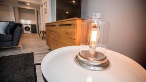 Ein modernes Wohnzimmer mit einem runden weißen Tisch, einer Holzkommode und einem Sofa.
